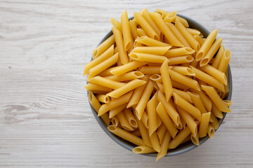 Raw Organic Dry Penne Pasta in a Bowl, top view. Overhead, flat lay, from above. Copy space.