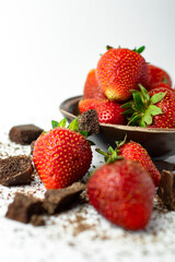 a view of a small piece of black porous chocolate lying with a dessert of red, fresh strawberries