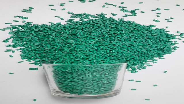 Portrait video of turquoise masterbatch granules spilling from a sloki on a white background.Color pigment carrier polymers in the plastics industry