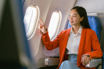 Asian woman sitting on airplane and looking out window, travel concept, tourism, business