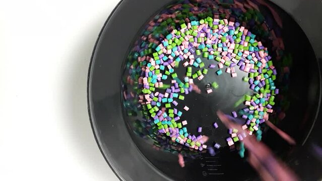 various colors of mixed masterbatch granules fall into a black measuring cup.color pigment carrier polymer in the plastics industry