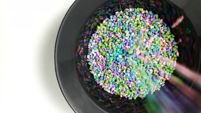 various colors of mixed masterbatch granules fall into a black measuring cup.color pigment carrier polymer in the plastics industry
