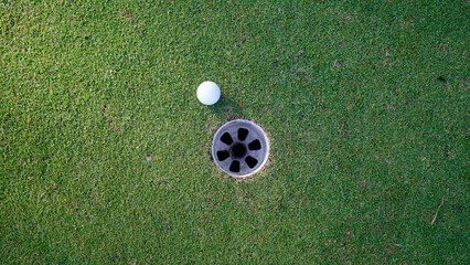 Naklejka premium Golf ball is on a green lawn in a beautiful golf course with morning sunshine.