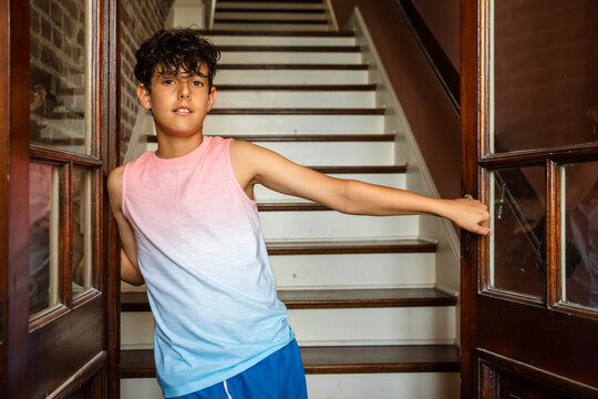 Handsome smiling boy standing in a doorway in front of stairs - Powered by Adobe