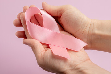 breast cancer, hands with ribbon symbol on pink background, oncology treatment patient hope