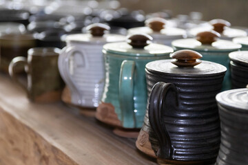 Handmade ceramic coffee mugs with wooden lids.