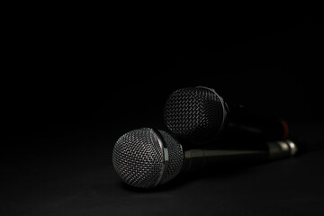 Black and silver microphones in the studio on a black and dark background. Professional recording equipment. Top view.