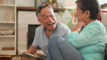 old asian senior couple packing cloth and stuff for a trip together,happiness asian old age retired mature adult enjoy arrange cloth together on floor at living room at home interior background - Powered by Adobe