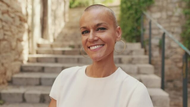 Close-up portrait of a smiling woman with very short hair
