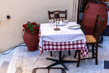 Table for two people in outdoor restaurant the Plaka region, Athens. There are cutlery on the table. Quiet place for dinning. 