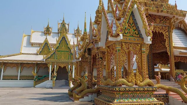 A large and beautiful crematorium  It is white and gold.  There are delicate Thai patterns on various parts.  Both pillars and gables and the roof have high chimneys to vent smoke.  There is a small p
