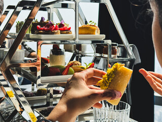 Guests interactively select from an array of decadent and beautifully arranged desserts and savory items served on a modern mirrored tiered tray.