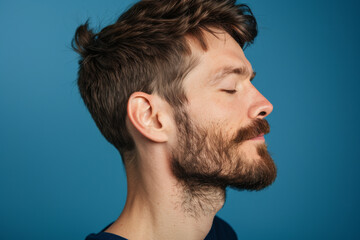 Obraz premium A close up of a man with beard and closed eyes looking to a side