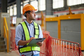 Worker writing and checking on clipboard at train construction site