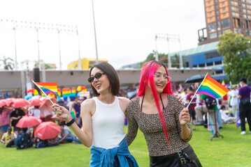 Happy young asian lesbian couple with pride movement LGBT holding rainbow flag raise up for...