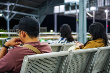 Passengers play with smartphones while waiting for their train on the train platform