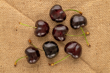 Several ripe sweet cherries  on a jute cloth, macro, top view.