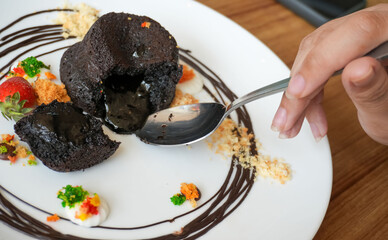 Delicious chocolate fondant or lava cake with cream, strawberry, and cake biscuit crumbles, Hot chocolate dessert pudding with liquid chocolate center, fondant au chocolate