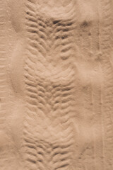 Background, texture of the uneven surface of traces, imprints from wheels, car tires on a sandy...