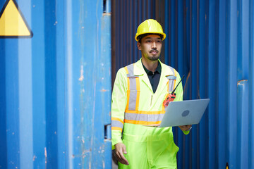 worker or engineer holding laptop computer and look around in containers warehouse storage
