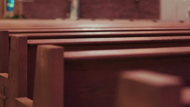 Slow-motion dramatic shot of empty wooden church pews.