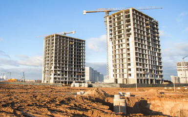 Tower cranes constructing a new residential build. Pouring concrete into formwork of building at construction site. Laying or replacement of underground storm sewer pipes. Concrete drainage pipe.