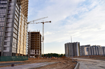 Laying paving slabs and borders at construction site. Tower cranes in action with machinery and builders. Crane build the high-rise building. New residential skyscraper. Tall house renovation project
