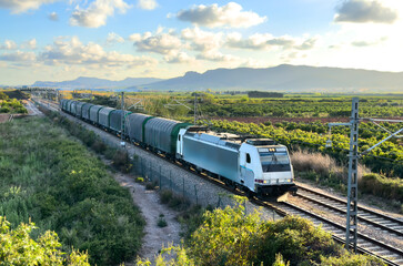 Freight train transports cargo and freight. Diesel locomotive on railway in Spain. Train on railroad. Freight Train with shipping containers. Rail Freight Shipping Logistics, Maritime containers