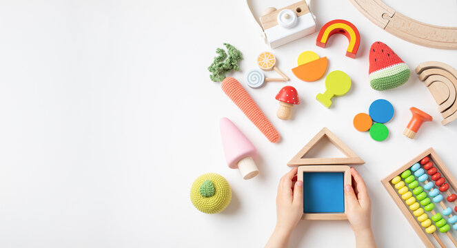 Toddler children activity for motor and sensory development. Baby hands with colorful wooden toys on table top view.