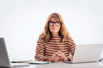 Blond haired mid aged businesswoman using laptops against isolated background