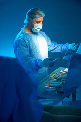 Doctor surgeon preparing sterile medical instruments for operation