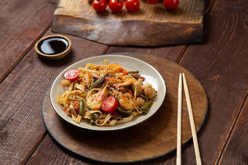 shrimp udon yaki soba sauce on a round stand next to soy sauce and chopsticks.