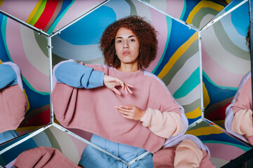 Young woman posing in hexagon mirrors on colorful background with kaleidoscope effect