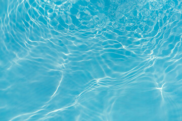 Blue water with ripples on the surface. Defocus blurred transparent blue colored clear calm water surface texture with splashes and bubbles. Water waves with shining pattern texture background.