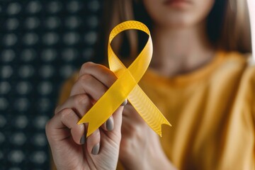 A woman is holding a yellow ribbon that says "breast cancer awareness.". The ribbon is a symbol of support for those affected by breast cancer