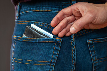 pickpocket, thief stealing money from the pocket, hand closeup