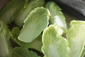Chinese cabbage leaves in water inside sink, above view