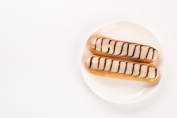 Delicious eclairs covered with glaze on white background, top view