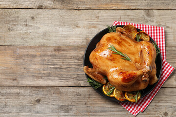 Tasty roasted chicken with rosemary and lemon on wooden table, top view. Space for text