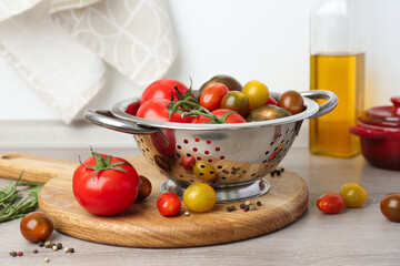 Metal colander with fresh tomatoes on wooden table