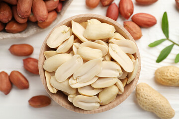 Fresh peanuts and twig on white wooden table, flat lay