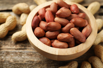 Fresh unpeeled peanuts in bowl on wooden table