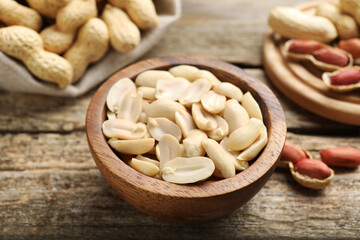 Fresh peanuts in bowl on wooden table, closeup