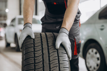 Close-up Car Mechanic holding a tire at the repair garage. Replacement of winter and summer tires © anatoliycherkas