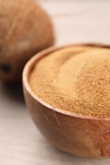Coconut sugar in bowl on light wooden table, closeup