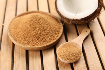 Coconut sugar, spoon, plate and fruit on wooden table, closeup
