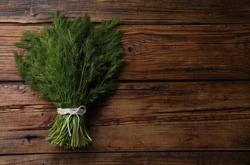 Bunch of fresh green dill on wooden table, top view. Space for text