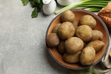 Tasty young boiled potatoes in bowl served on grey table, flat lay. Space for text