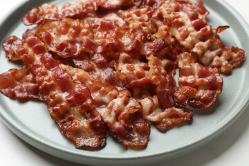 Slices of tasty fried bacon on white table, closeup
