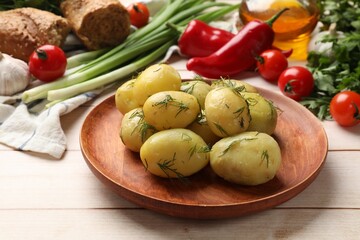 Tasty young boiled potatoes with dill and other products on wooden table